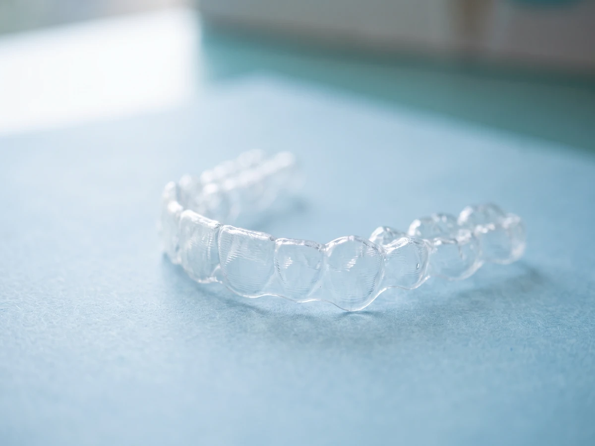 Concept illustration: a clear aligner tray on pale blue paper